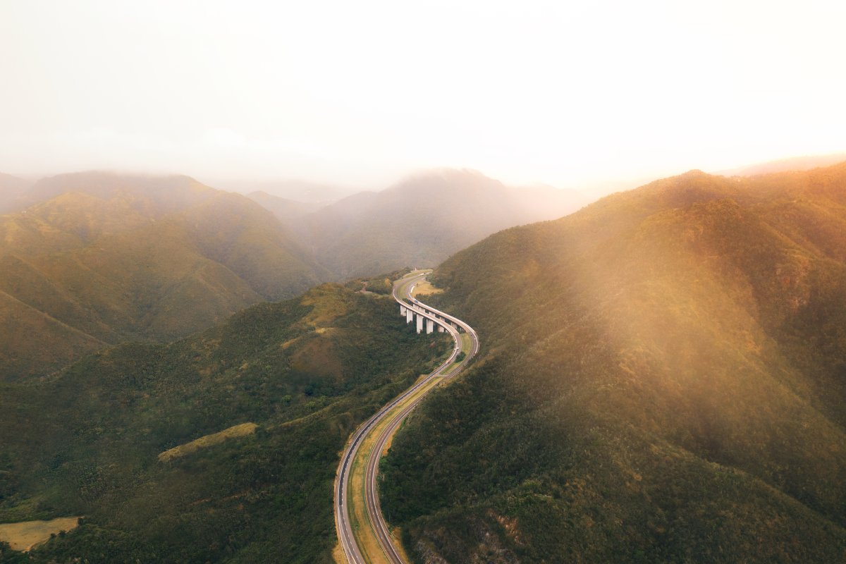 Aerial shot showing a curving stretch of highway winding through a mountain pass