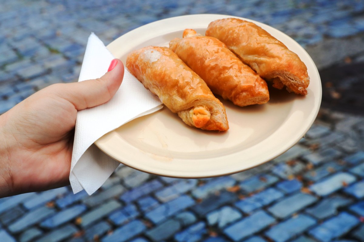 A woman's hand holding a plate with quesitos.