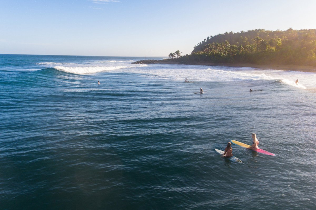 Local and visiting surfers in the water waiting for the next big wave at Domes Beach in Rincón, Puerto Rico.