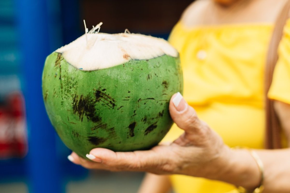 Una mujer sostiene un coco fresco en los Kioskos de Luquillo.