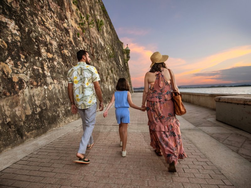 A family walks oceanside along the Paseo de la Princesa in Old San Juan.