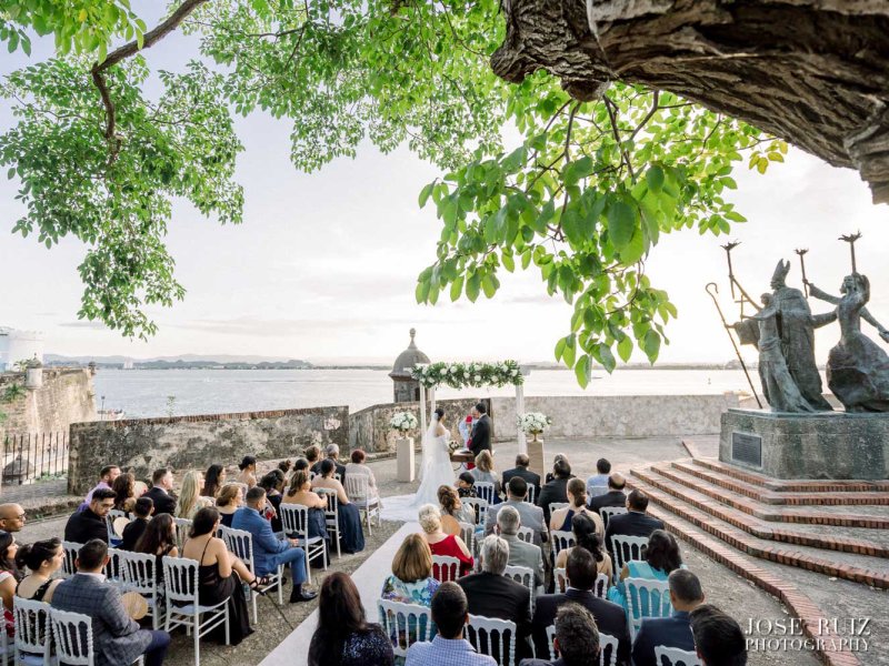 Invitados sentados para una boda frente a la icónica estatua de La Rogativa en el Viejo San Juan.