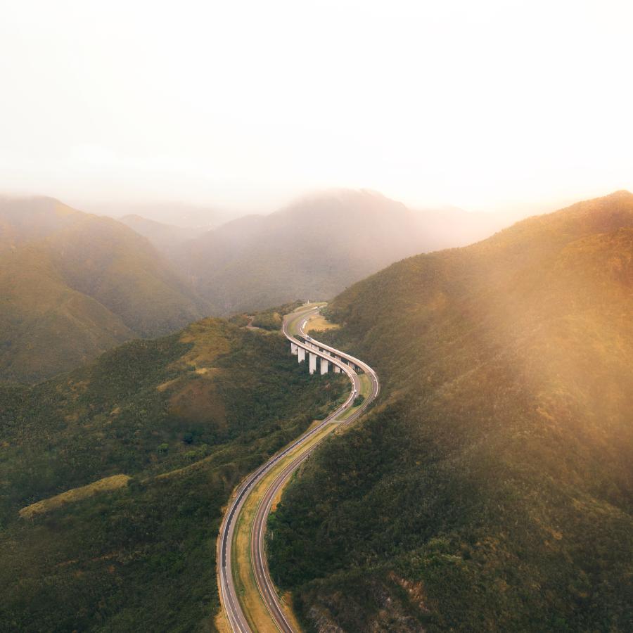 Aerial shot showing a curving stretch of highway winding through a mountain pass