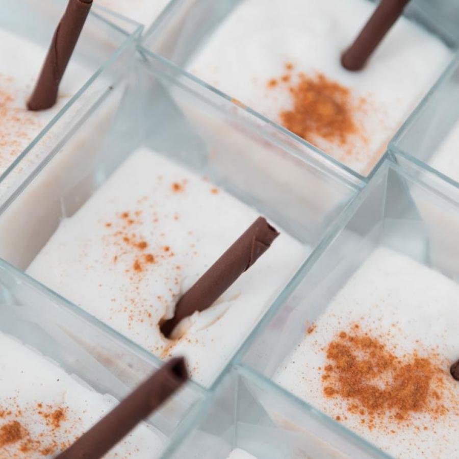 Cups filled with tembleque and cinnamon sticks.