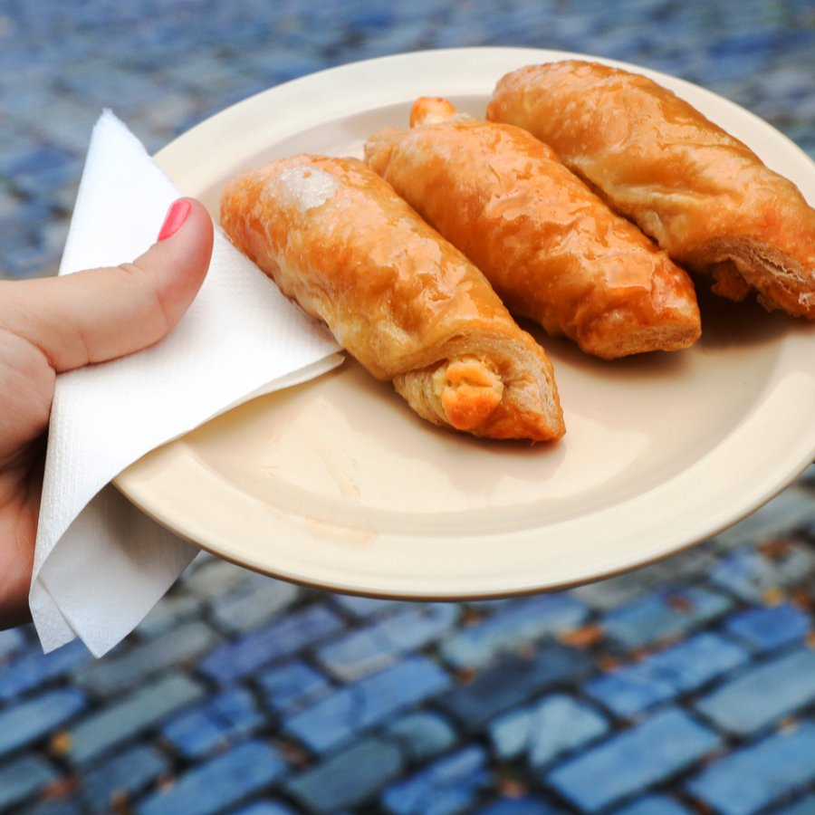 A woman's hand holding a plate with quesitos.