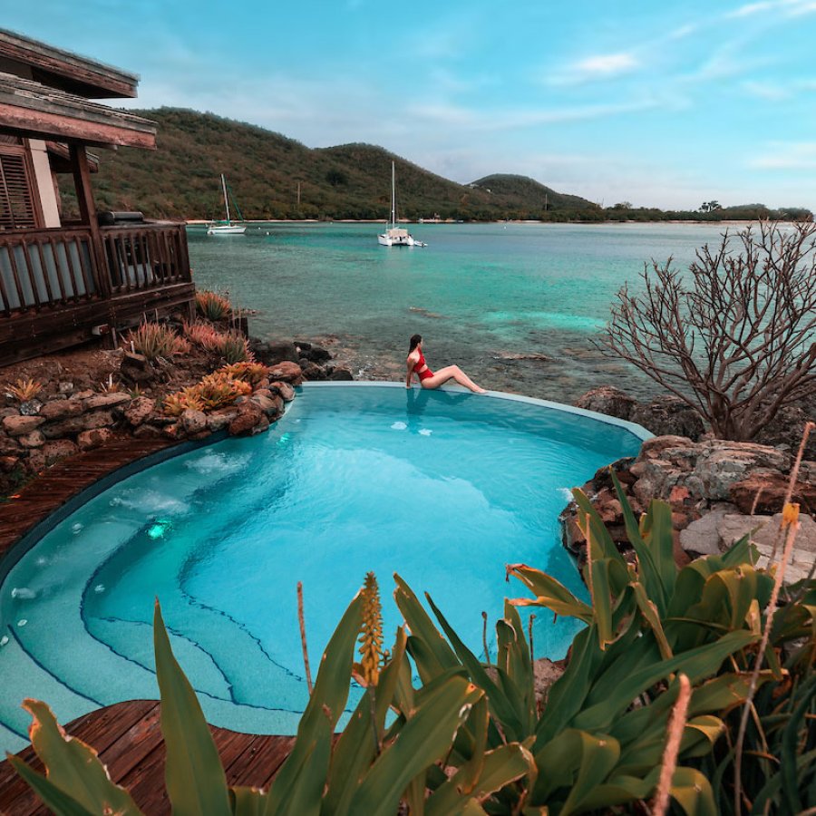 A woman perches on the edge of a private pool overlooking the ocean at a vacation rental in Puerto Rico.