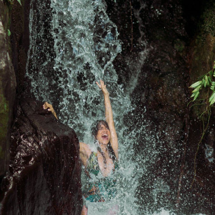 A woman plays under a waterfall in Puerto Rico.