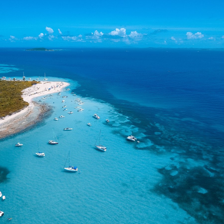 Overhead view of the coastline of Cayo Icacos on the east coast of Puerto Rico, with clear-blue water and several boats anchored near the shore.