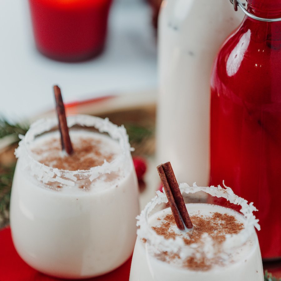 Coquito glasses are decorated with cinnamon sticks. 