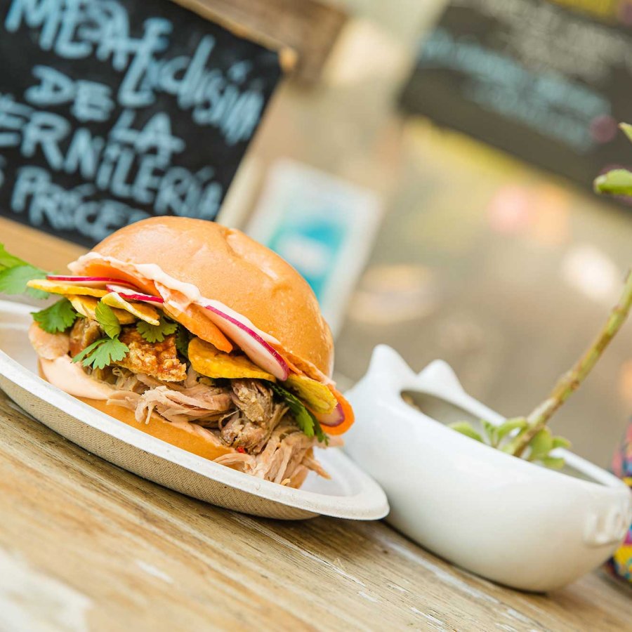 A sandwich with many toppings and a colorful can of beer are pictured on a table at Lote 23, a food truck park in the Santurce neighborhood of San Juan, Puerto Rico.