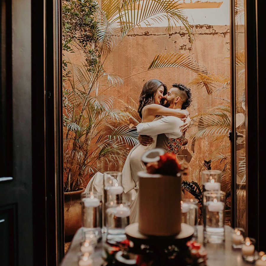 A couple embraces on a balcony with a wedding cake in the foreground at El Convento in San Juan, Puerto Rico.