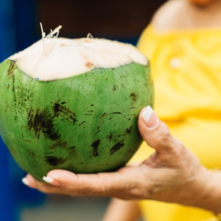 Una mujer sostiene un coco fresco en los Kioskos de Luquillo.