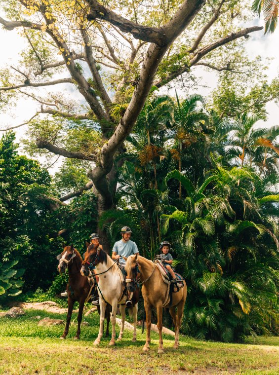 Family of three goes horseback riding in a lush hacienda.