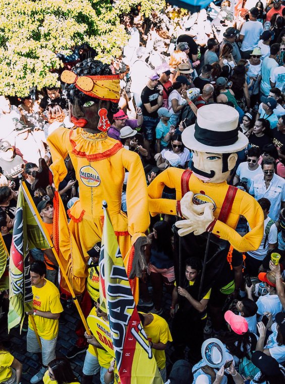 Large puppets being carried among a large crowd of people